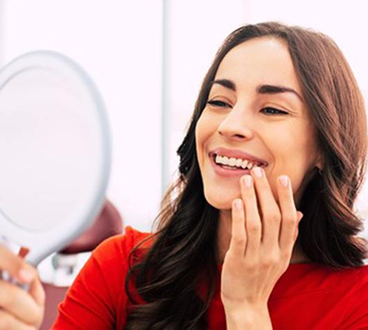 a patient smiling and admiring her new dental bridge in New Bedford