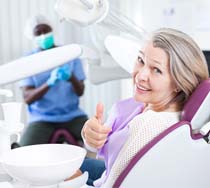 Dental patient giving thumbs up for preliminary dental implant treatment