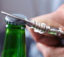 green bottle being opened with bottle opener 