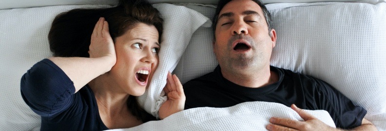 Woman frustrated next to snoring man in need of sleep apnea therapy