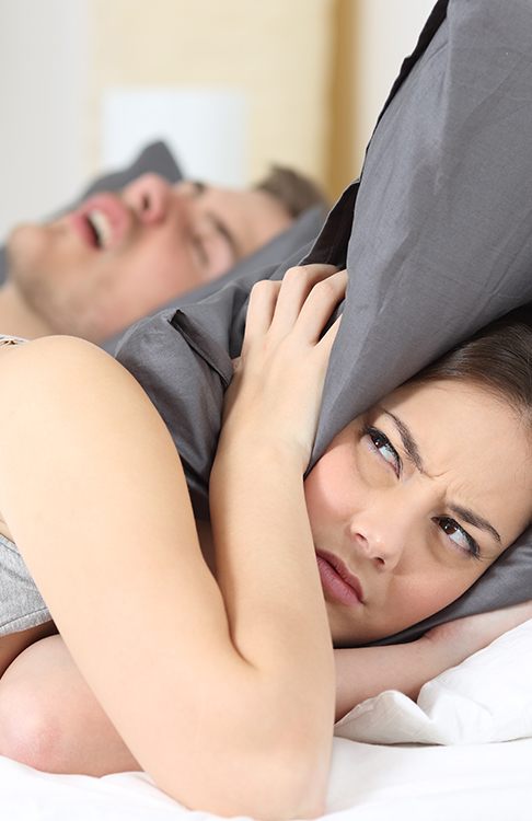 Frustrated woman next to snoring man who needs sleep apnea therapy
