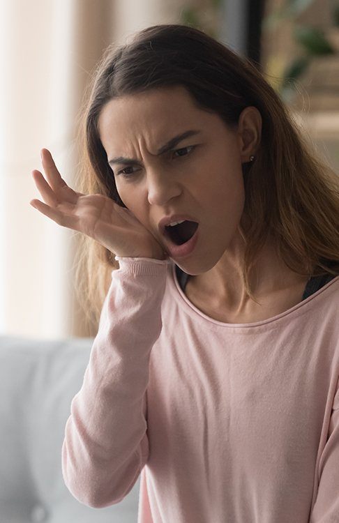 Woman in need of T M J therapy holding jaw in pain