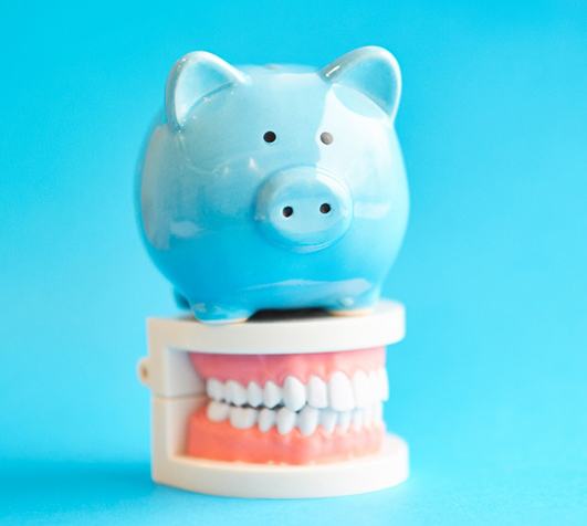 A blue piggy bank sitting on top of model dentures