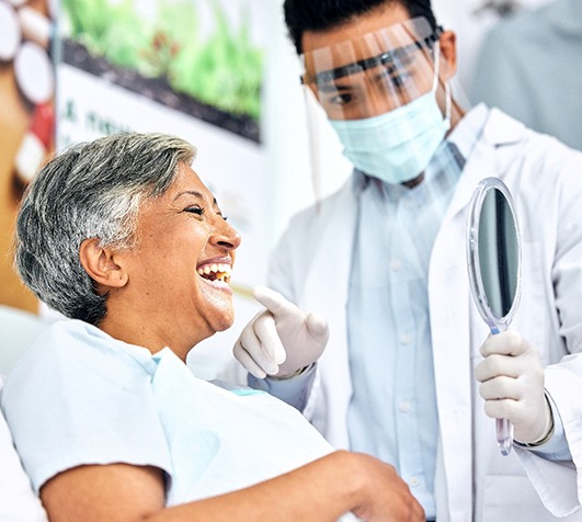 Dentist showing patient their smile in handheld mirror