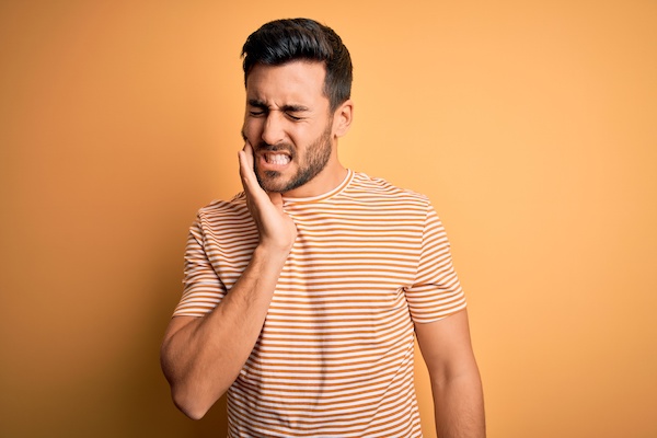 man experiencing a toothache, orange background