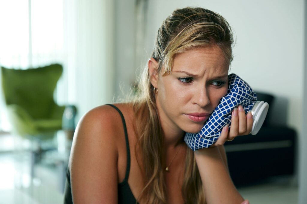 Woman in pain holding checkered cold compress to her jaw