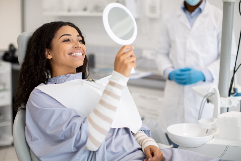 a patient checking her smile with a mirror