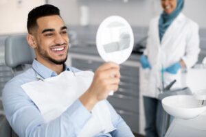 Handsome dental patient looking at his smile in mirror